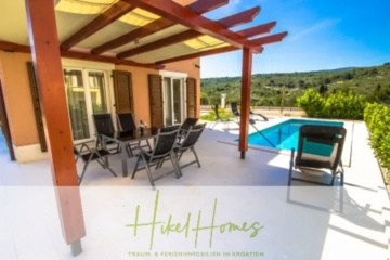 Terrasse mit Pergola, Gartenmöbeln und Swimmingpool mit Blick auf eine üppig grüne Landschaft unter einem klaren blauen Himmel. Die Textüberlagerung lautet „Hikel Homes“ mit zusätzlichem Text über Immobilien in Kroatien. - Villa im Mittelmeerstil mit 3 SZ, Pool, Dachterrasse mit Meerblick (1)