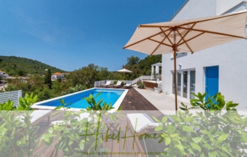 Eine moderne Villa mit blauem Swimmingpool und Sonnenliegen auf einer Holzterrasse. Große Sonnenschirme spenden Schatten. Die Villa ist von viel Grün umgeben, mit einem klaren blauen Himmel und im Hintergrund sind in der Ferne Hügel zu sehen. Die Textüberlagerung lautet „Hikel Homes“. - 2 Meerblick Villen + freies Grundstück ideal zur Vermietungauf der Insel Dugi Otok jeweils mit Pool