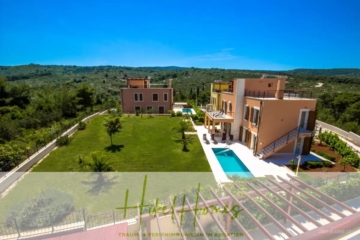 Luftaufnahme von zwei modernen Häusern mit Terrakotta-Dächern, jedes mit Pool, gelegen auf einem großen, gepflegten Rasen. Im Hintergrund ist eine üppige, grüne Landschaft unter einem klaren blauen Himmel zu sehen. - Villa im Mittelmeerstil mit 3 SZ, Pool, Dachterrasse mit Meerblick (3/4)